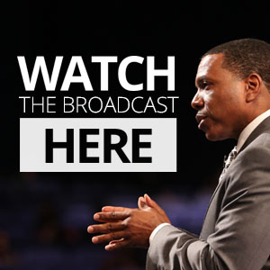 Creflo Dollar preaching in a grey suit with the text “Watch the Broadcast Here”
